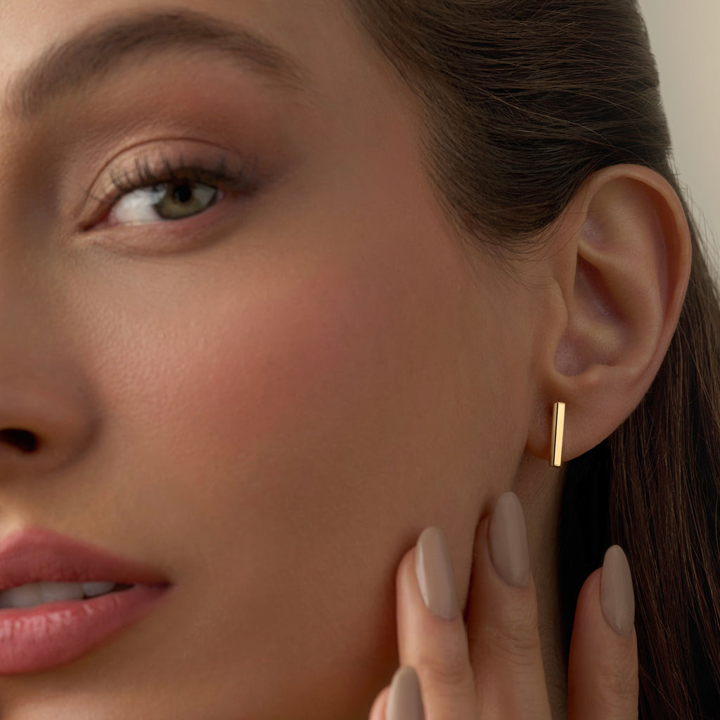 Model wearing 14K Yellow Gold Little Bar Earrings, highlighting their sleek minimalist design and secure push-back closures.