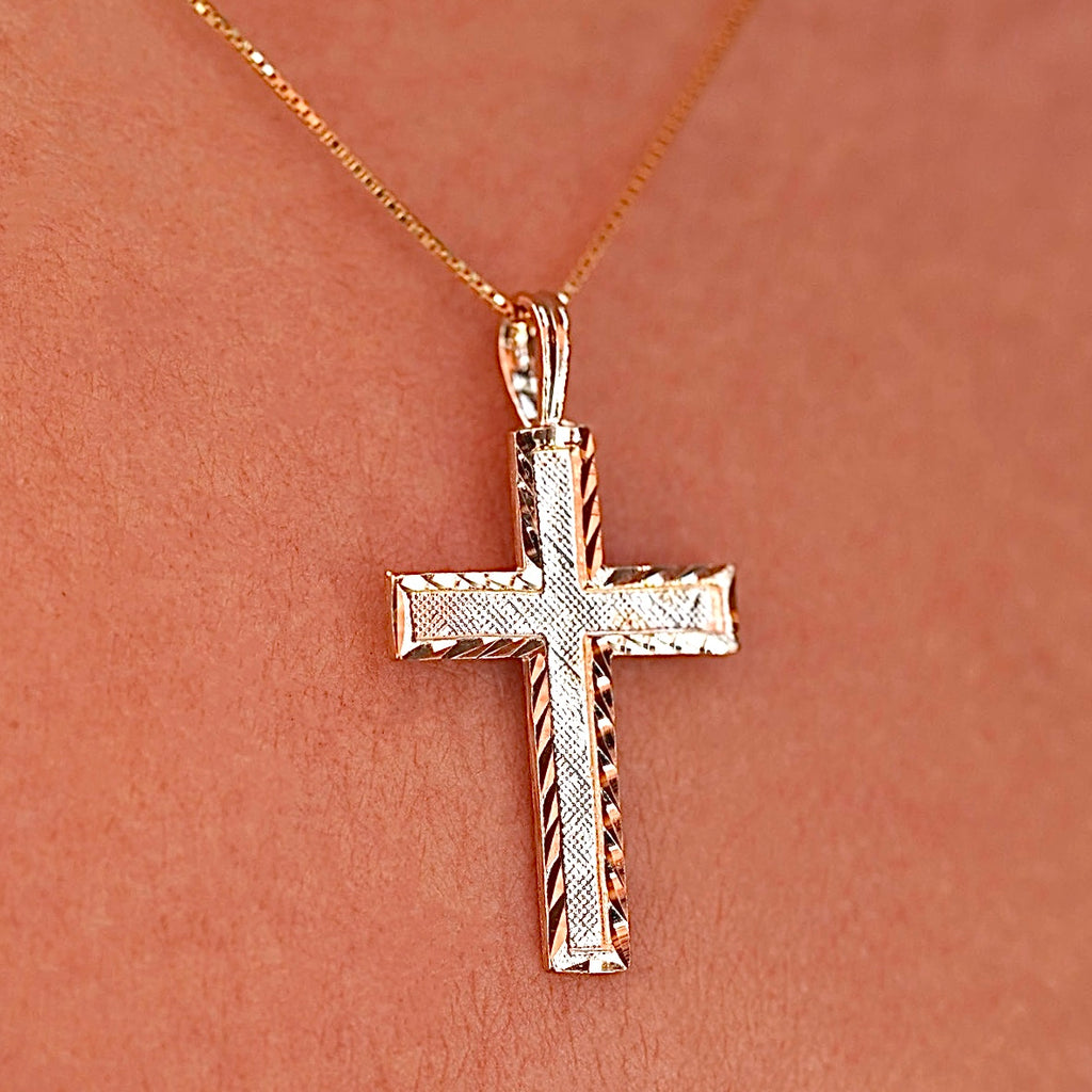 A model wearing the gold Latin cross pendant on a delicate chain, the charm sitting gracefully on her neckline with a soft glow.