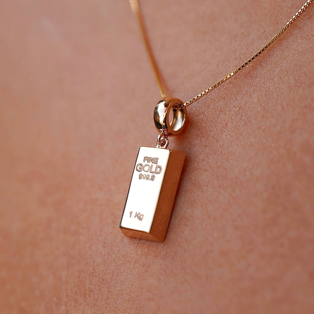 Close-up of a model wearing a 14K yellow gold bar pendant, the gleaming gold piece catching the light and offering a modern, refined jewelry statement.