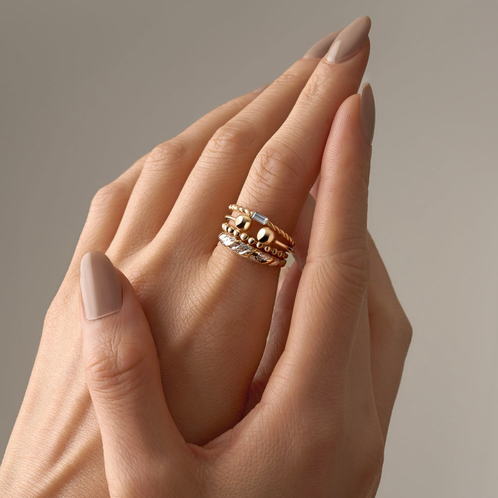 Close-up of a model’s hand wearing the 14K Yellow Gold Stackable CZ Ring stacked with other gold rings, showcasing a stylish layered jewelry look.