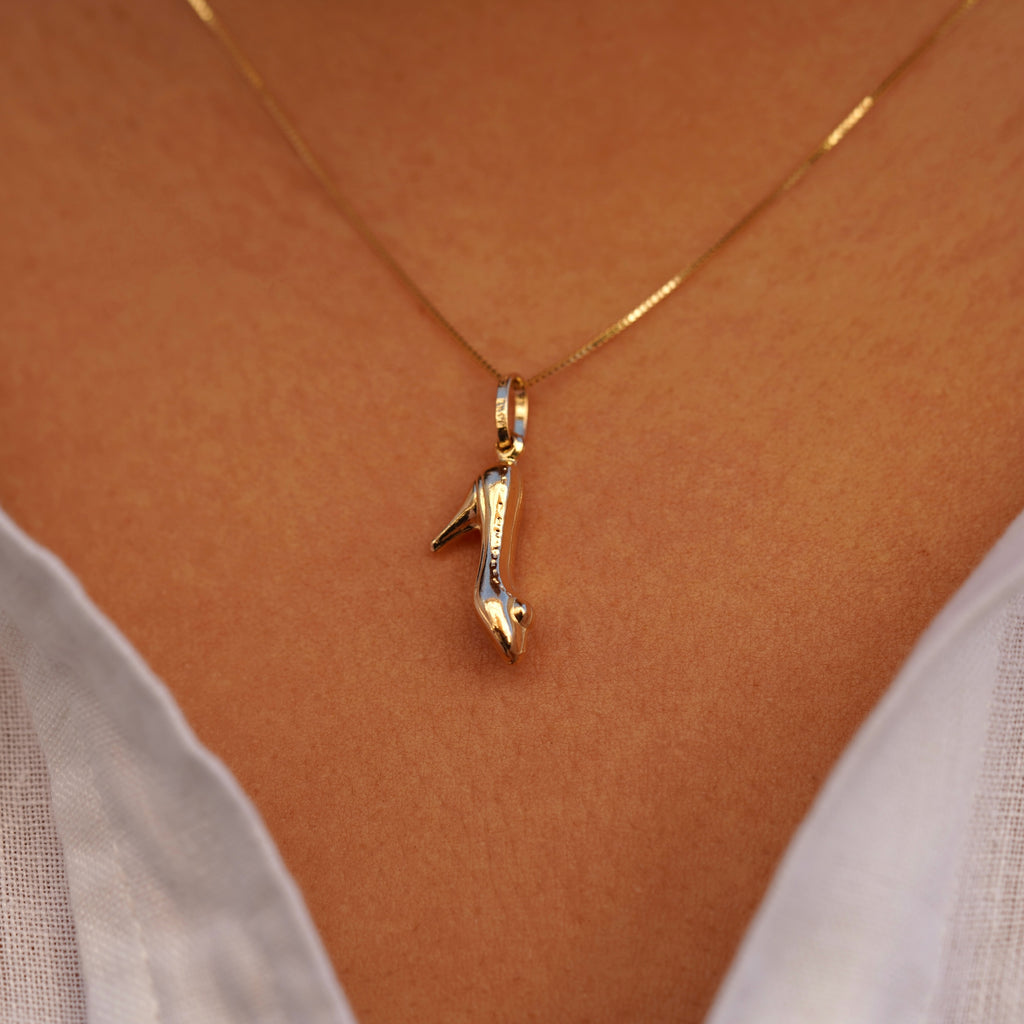 A model wearing the 14K solid gold high heel shoe charm pendant on a delicate gold chain around the neck. The charm rests just below the collarbone, adding a stylish and subtle touch to the model’s outfit. The lighting highlights the pendant’s rich yellow gold hue and refined craftsmanship, illustrating how this dainty charm enhances any fashion look with sophistication.