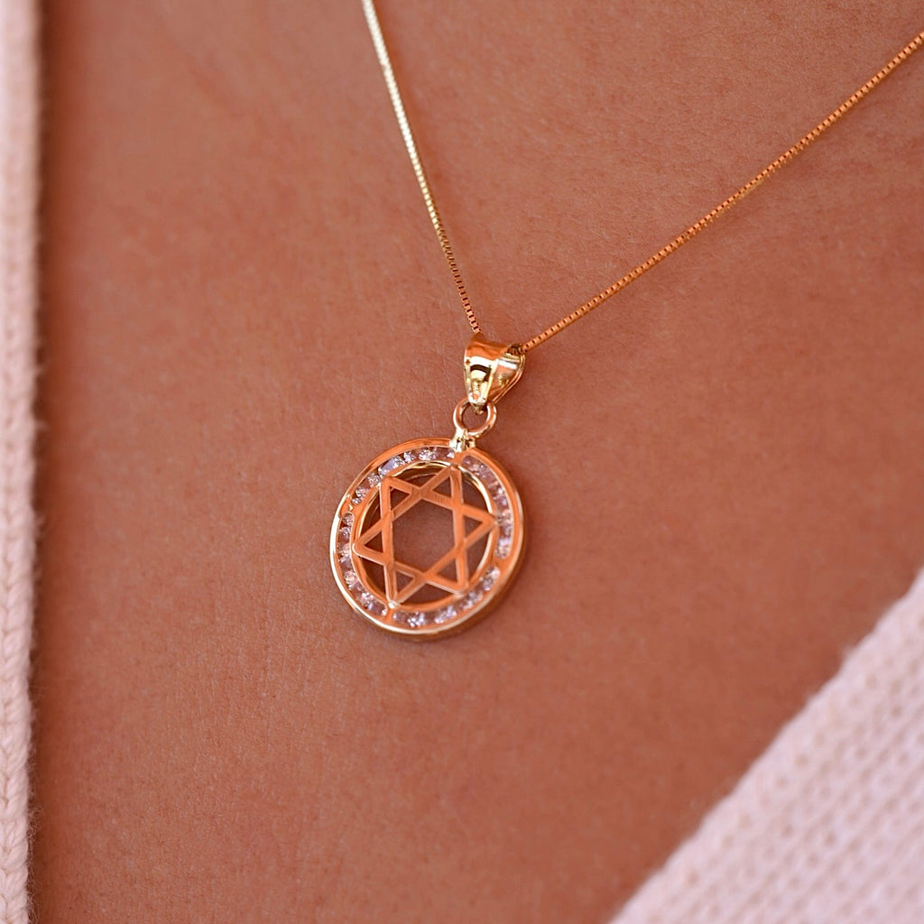 A model wearing the 14K gold Star of David pendant on a delicate gold chain, showcasing how the spiritual charm rests beautifully against the skin, with the CZ stones adding subtle sparkle.