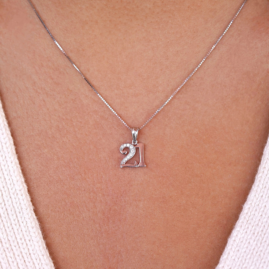 A model wears the 14K white gold "21 Years" charm pendant on a matching white gold chain, with cubic zirconia sparkling subtly under natural light—capturing the elegance and significance of a milestone birthday.
