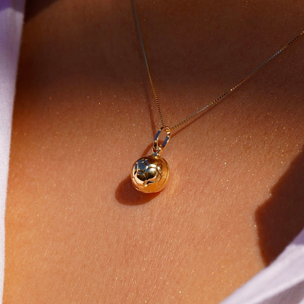 Model wearing 14K yellow gold soccer ball pendant on a thin chain, styled as a sporty-chic necklace.