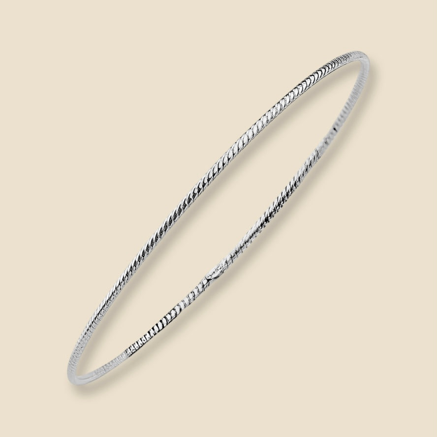 A dainty 14K white gold braided bangle bracelet with a delicate 1.5mm rope design, placed against a plain background. The warm golden tone and intricate twist pattern reflect light softly, highlighting the elegant craftsmanship.