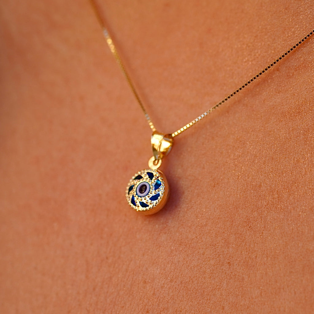 A model is wearing the 14K gold Evil Eye pendant with a blue eye on a fine chain, allowing the charm to rest beautifully against the skin. The striking blue eye adds a subtle yet meaningful touch, perfect for everyday wear.