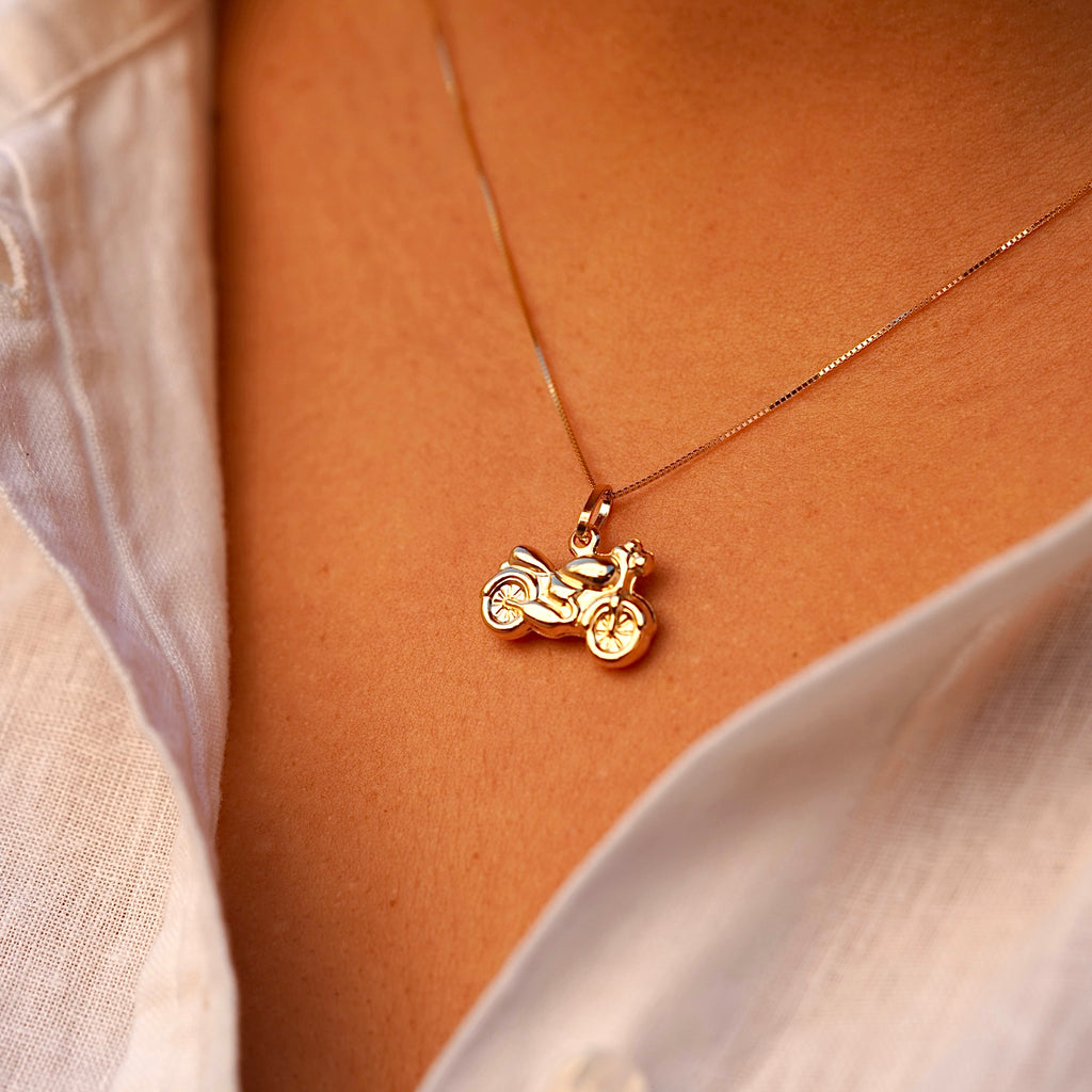 A close-up of a model wearing the 14K gold motorcycle charm pendant on a chain, highlighting its bold design and stylish biker aesthetic.