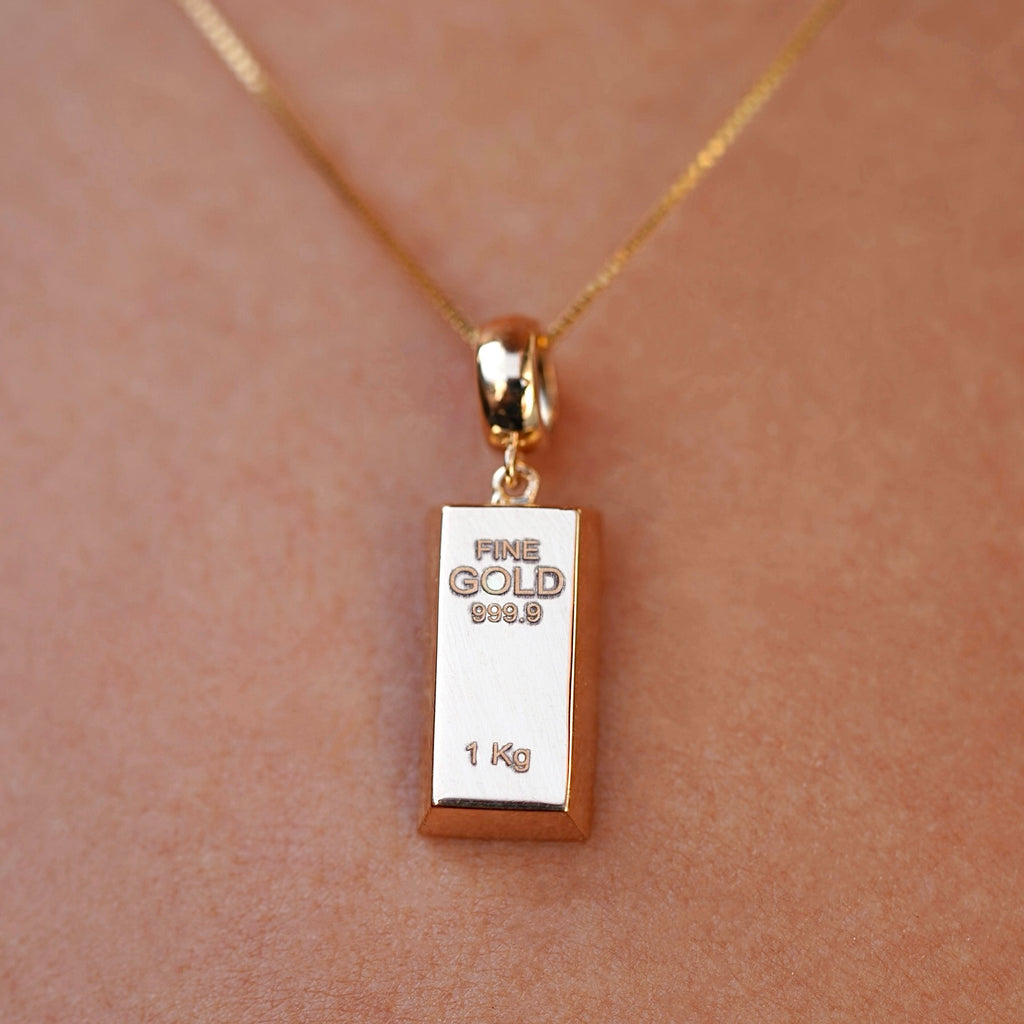 Close-up of a model wearing a 14K yellow gold bar pendant, the gleaming gold piece catching the light and offering a modern, refined jewelry statement.