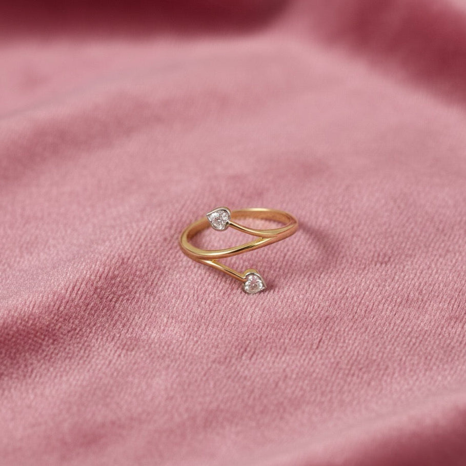 High-polish 14K yellow and white gold fancy ring adorned with cubic zirconia stones, photographed on a pink fabric to highlight its shine and texture.