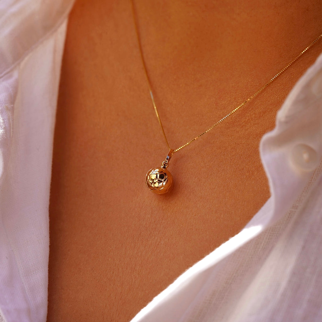 Model wearing 14K yellow gold soccer ball pendant on a thin chain, styled as a sporty-chic necklace.