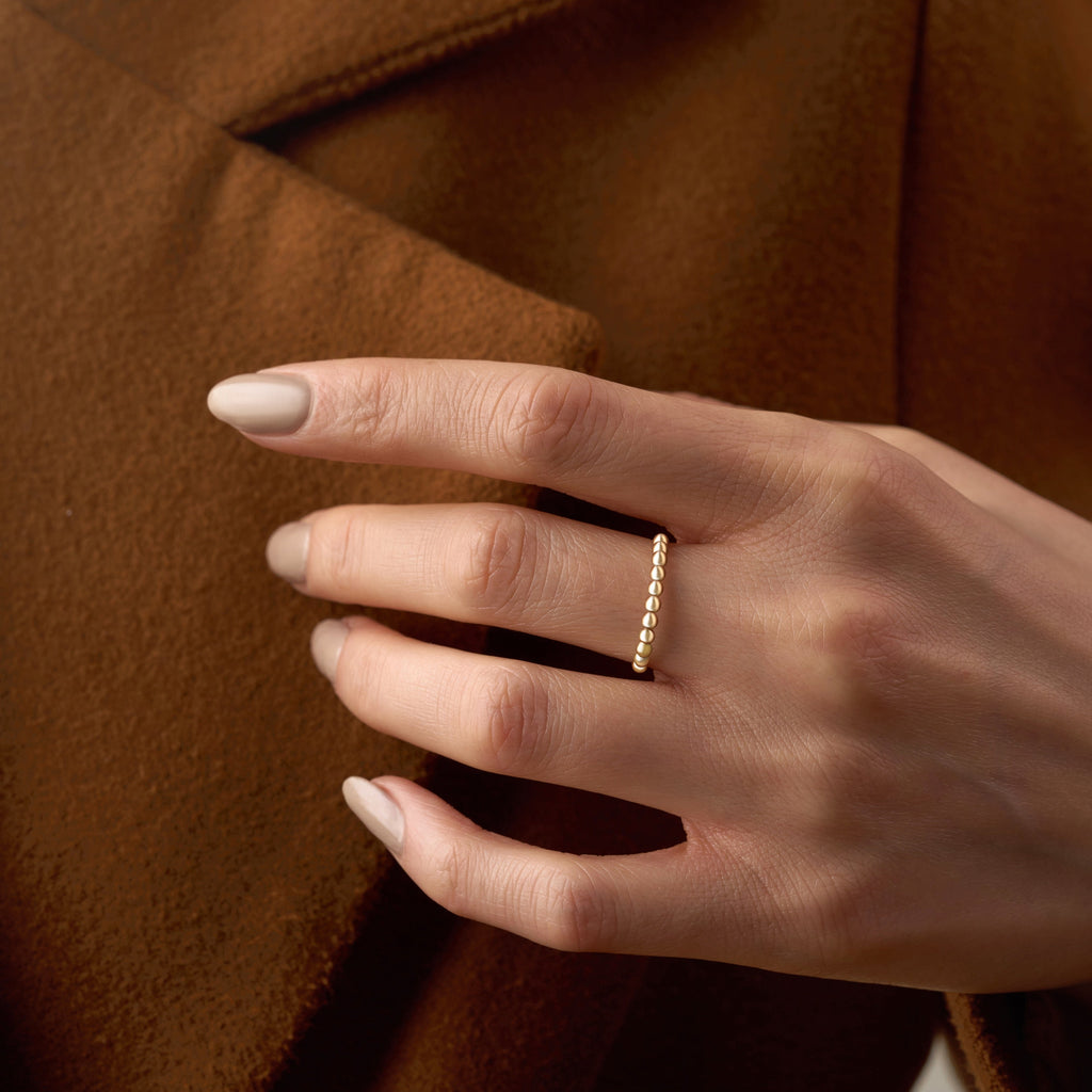 A model wearing the 14K yellow gold polish ball ring on her hand, showcasing its delicate row of polished gold beads. The ring’s minimalist and dainty design adds a subtle shine to the model’s elegant look, perfect for everyday wear or stacking with other fine gold rings