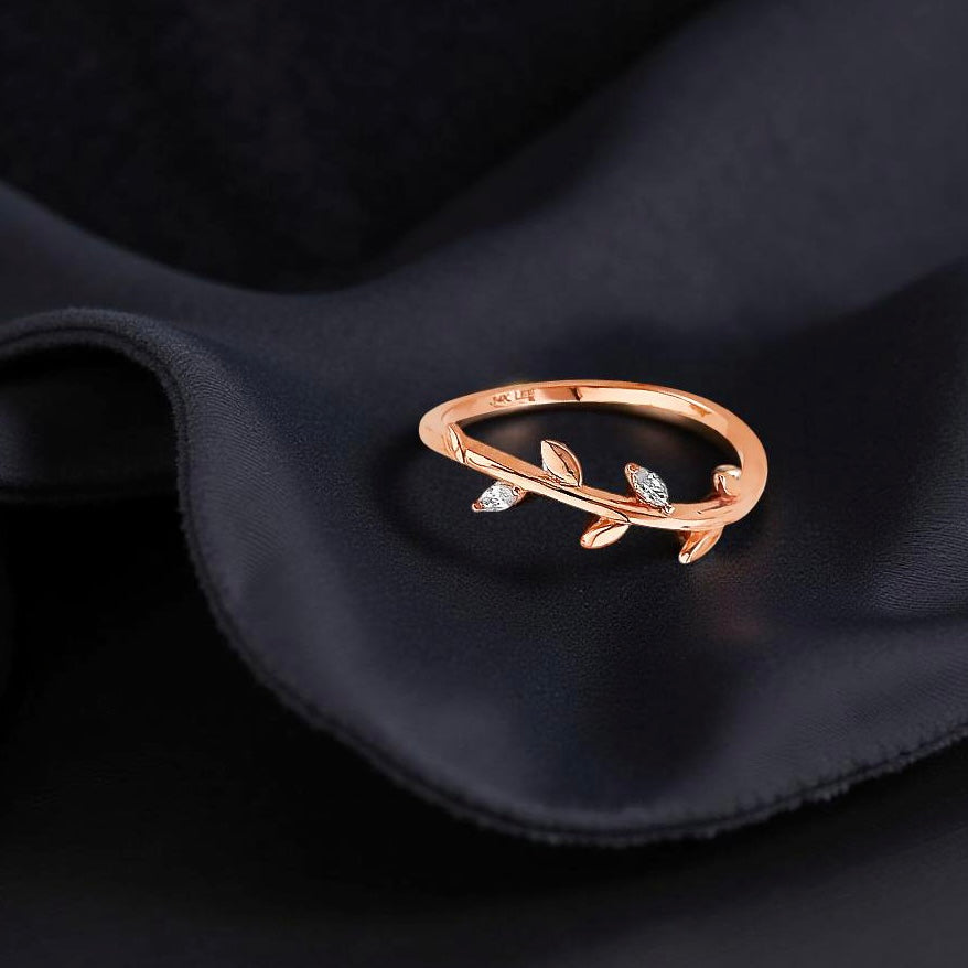 Elegant 14K rose gold ring laying on a black fabric, highlighting the curved leaf shape and shimmer.