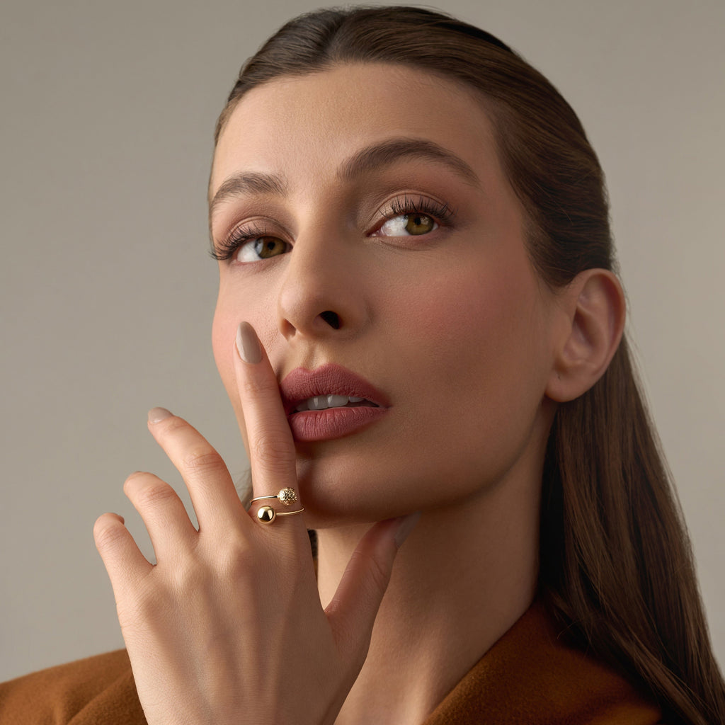 A model wearing a 14K yellow gold beaded ball ring, the polished gold spheres reflecting light beautifully as the ring adds a touch of subtle sophistication to her look.