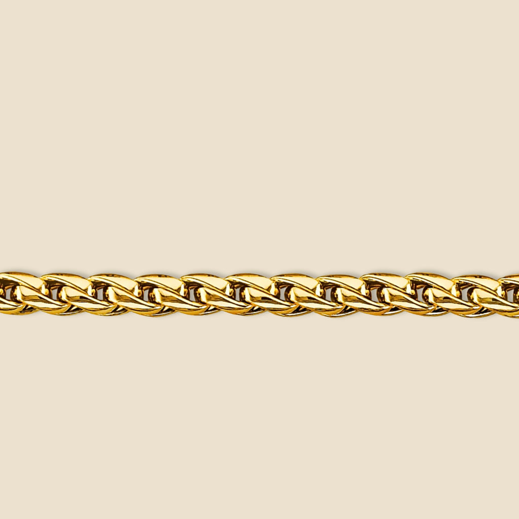 Close-up of 14K gold Franco bracelet resting on a plain background, highlighting the bracelet's polished finish and structured round link pattern.