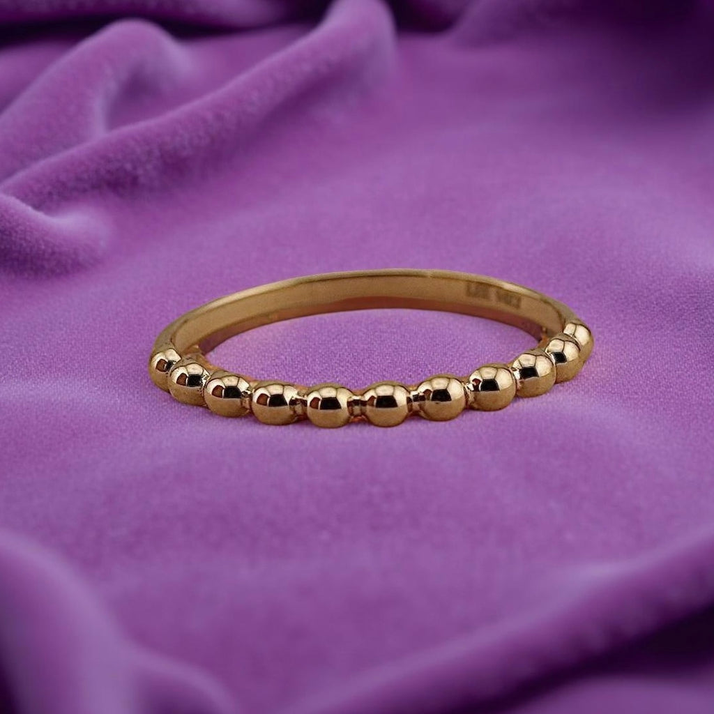 14K Yellow Gold Beaded Ring resting on a purple velvet, highlighting the gentle shine and minimalist bead detail in natural lighting.
