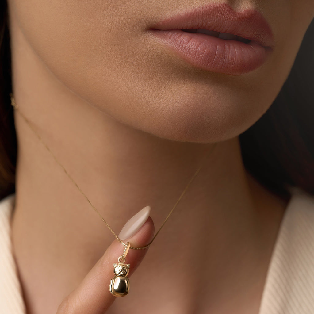 Model wearing a delicate 14K yellow gold cat pendant on a fine gold chain, showcasing its subtle shine and whimsical charm resting gracefully at the collarbone.