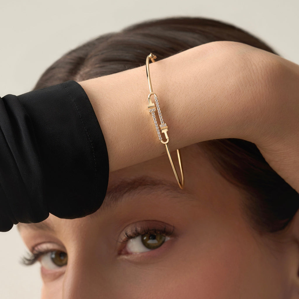 A model elegantly wearing a 14K yellow gold flexible bangle adorned with brilliant cubic zirconia stones. The bracelet glimmers softly under the light, highlighting its sleek, minimalist design and lightweight flexibility. The model’s wrist showcases how the bangle curves naturally for a comfortable, refined fit, perfect for everyday sophistication or special occasions. The yellow gold finish radiates warmth and luxury, complementing any modern, elegant style.