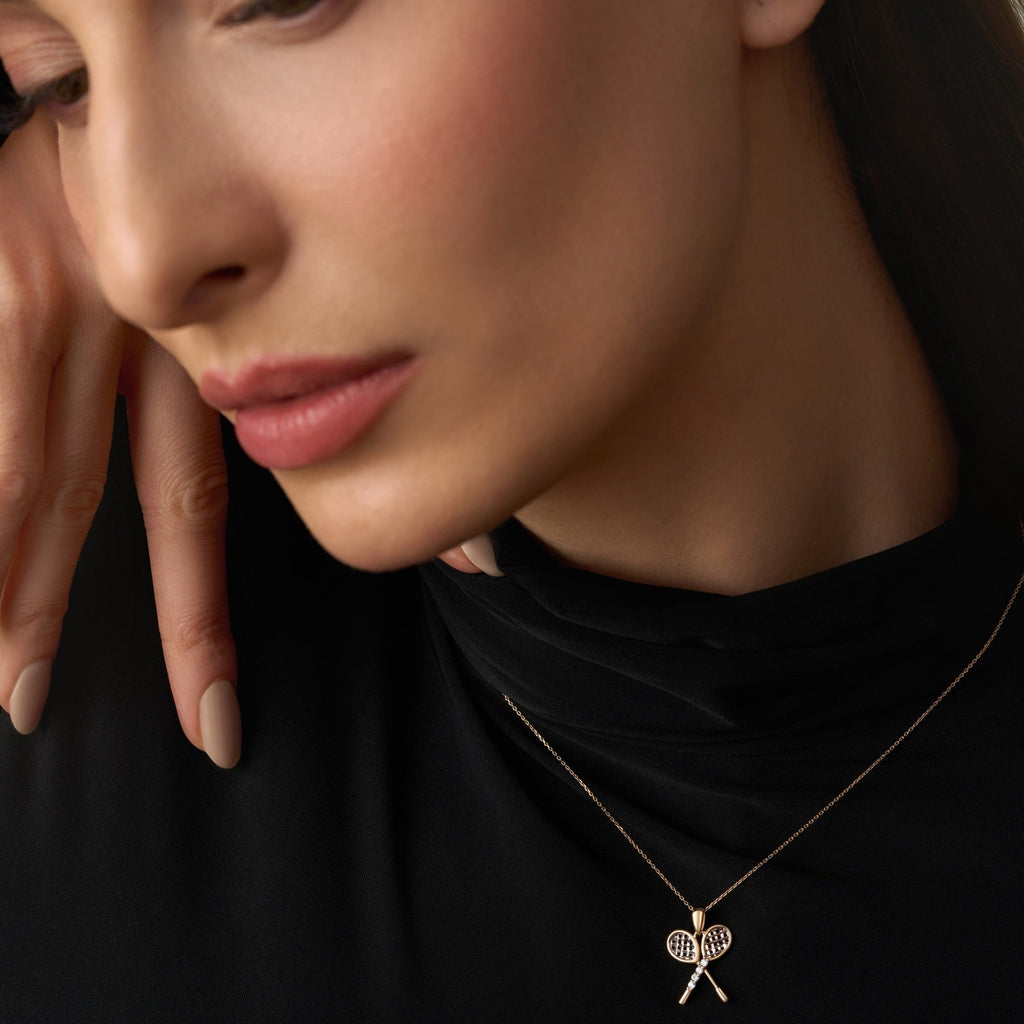 A model wearing the 14K Gold Tennis Racquet Pendant, showcasing its detailed two-tone design and sparkling CZ accents. Perfectly sized for layering or wearing alone, it blends sport-inspired charm with timeless elegance.