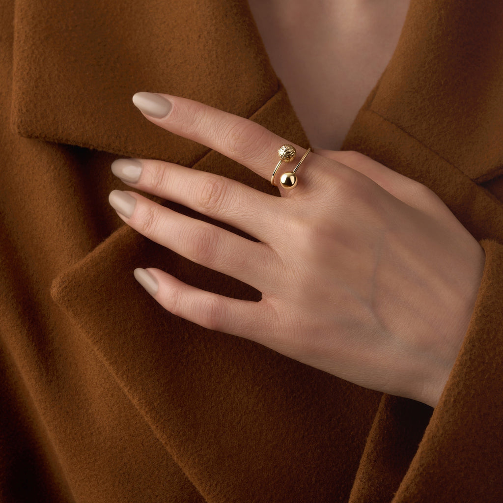 A model wearing a 14K yellow gold beaded ball ring, the polished gold spheres reflecting light beautifully as the ring adds a touch of subtle sophistication to her look.
