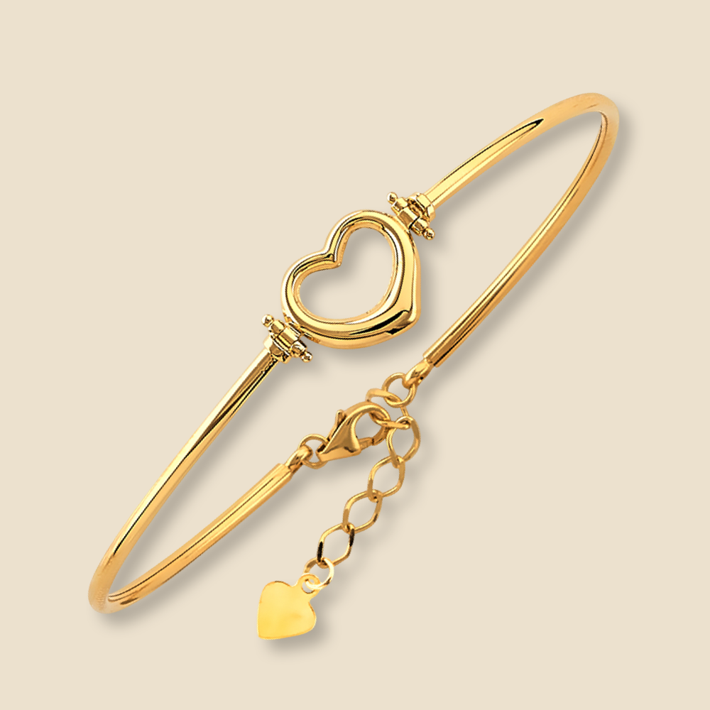 A polished 14K yellow gold heart oval bangle displayed on a plain background. The bracelet’s shiny surface and minimalist silhouette are highlighted clearly, with the heart symbol front and center, capturing its charm and fine detailing.