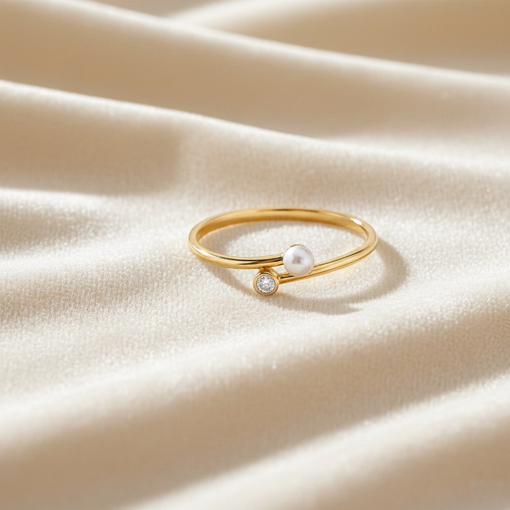 14K yellow gold pearl CZ ring resting on soft cream velvet cloth, showing the pearl and CZ details with gentle textured fabric beneath.