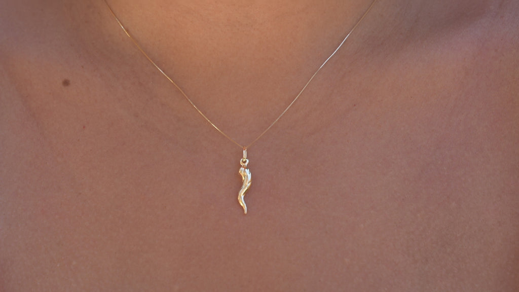 Model wearing the 14K Real Gold Twisted Cornicello Italian Horn Charm, gently lifting the chain and playing with it using her finger.