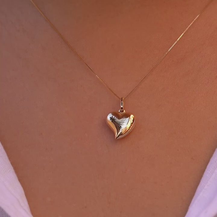 A model wearing the 14K Yellow Gold Hollow Heart Pendant on a fine chain, elegantly styled against her collarbone, highlighting its minimalist beauty.