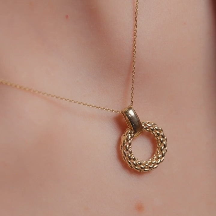 A model wears the 14K gold mesh pendant on a dainty gold chain, the intricate filigree design resting gracefully against her collarbone. The lightweight and elegant pendant adds a timeless touch to her outfit.