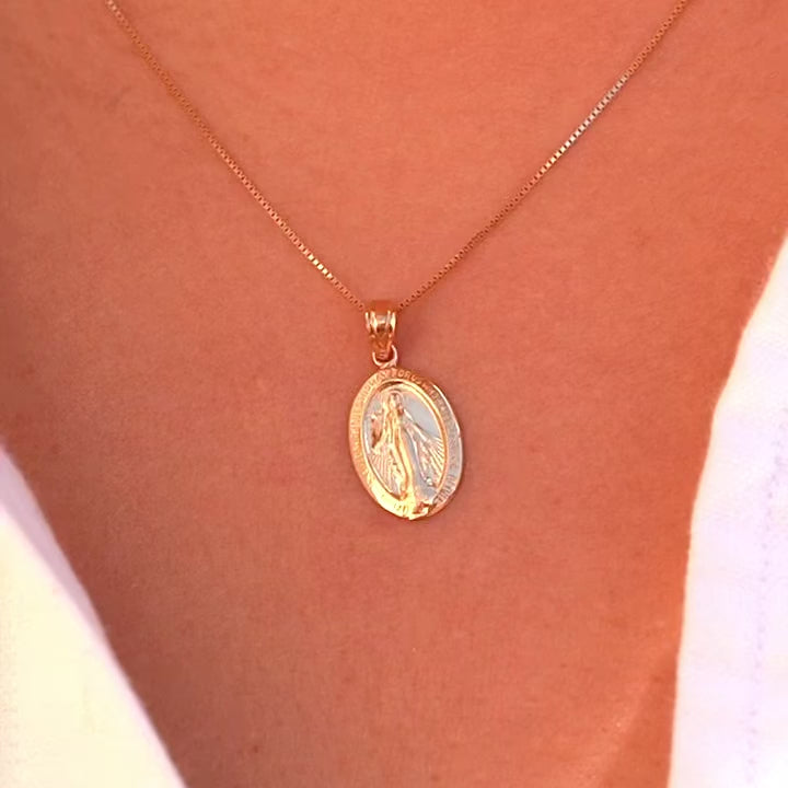 Model wearing a 14K gold Milagrosa pendant on a fine gold chain, the lightweight medallion resting at the collarbone, adding a subtle yet meaningful touch of faith.