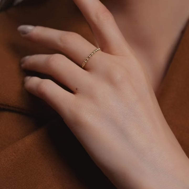 A model wearing the 14K yellow gold polish ball ring on her hand, showcasing its delicate row of polished gold beads. The ring’s minimalist and dainty design adds a subtle shine to the model’s elegant look, perfect for everyday wear or stacking with other fine gold rings