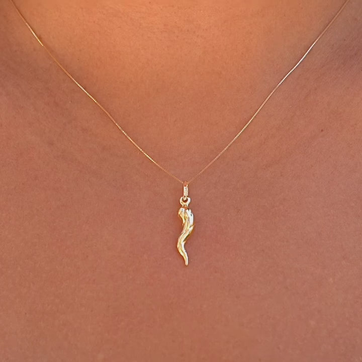 A stylish model wearing the 14K Gold Twisted Cornicello Italian Horn Charm on a delicate gold chain, showcasing its elegant twisted design and radiant gold finish. The pendant rests gracefully on the collarbone, adding a touch of Italian heritage and timeless charm to the outfit.