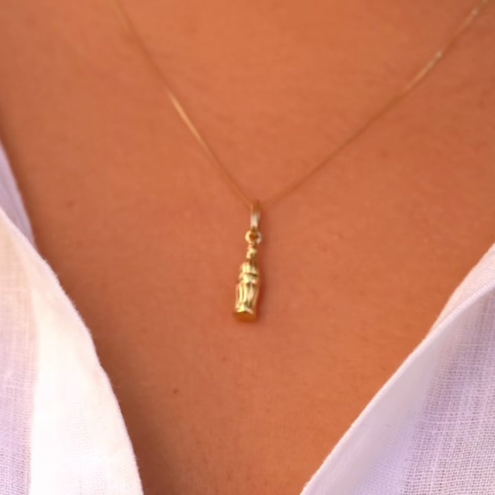 A close-up of a model wearing the 14K solid gold soda bottle pendant on a delicate chain, emphasizing its dainty and playful charm.