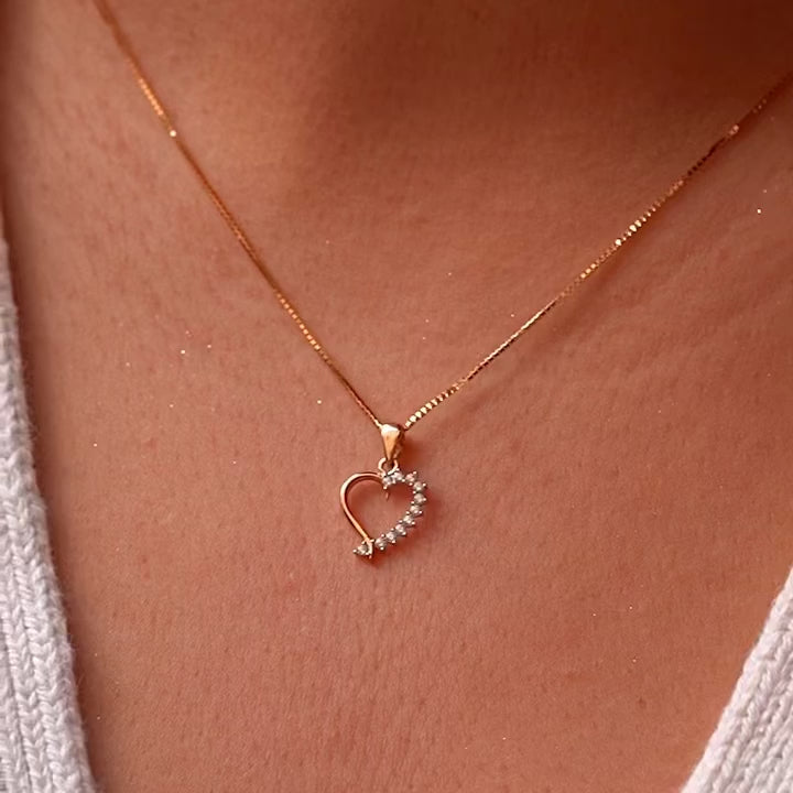 A delicate 14K Gold CZ Heart Pendant worn on a fine chain, elegantly resting against a model’s neckline, highlighting its dainty and elegant design.