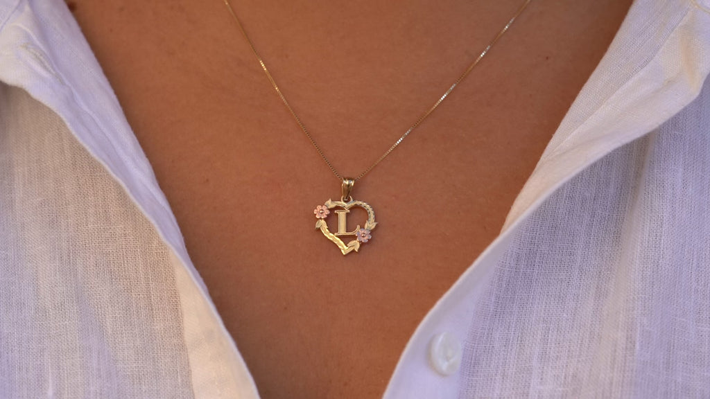 Model wearing the 14K Two-Tone Initial Heart Pendant with Letter L, showing the charm from various angles as it sparkles with yellow and rose gold detail.