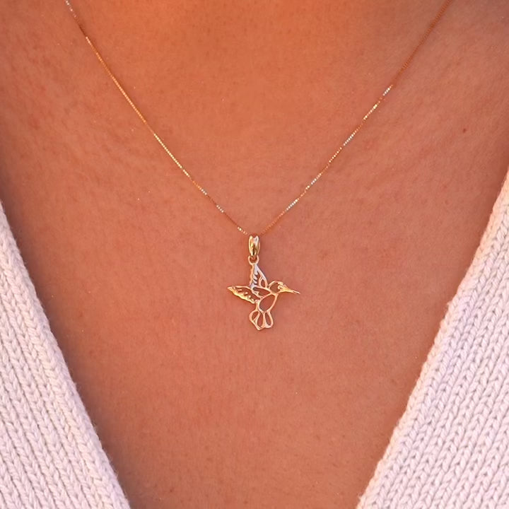 A model elegantly wears the 14K Yellow Gold Hummingbird Pendant on a delicate chain, highlighting its dainty size and the joyful charm it adds to her everyday style.