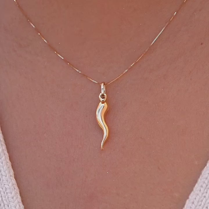 A model wearing a 14K yellow gold hollow horn pendant on a delicate chain, styled with a simple blouse for a minimalist and elegant everyday look.