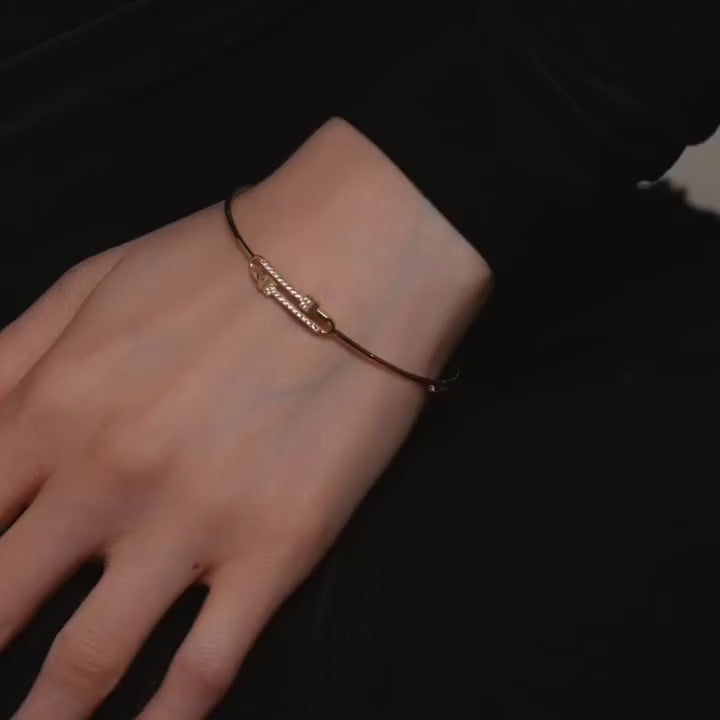 A model elegantly wearing a 14K yellow gold flexible bangle adorned with brilliant cubic zirconia stones. The bracelet glimmers softly under the light, highlighting its sleek, minimalist design and lightweight flexibility. The model’s wrist showcases how the bangle curves naturally for a comfortable, refined fit, perfect for everyday sophistication or special occasions. The yellow gold finish radiates warmth and luxury, complementing any modern, elegant style.