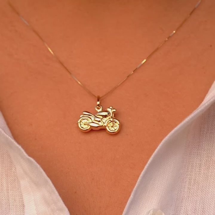 A close-up of a model wearing the 14K gold motorcycle charm pendant on a chain, highlighting its bold design and stylish biker aesthetic.