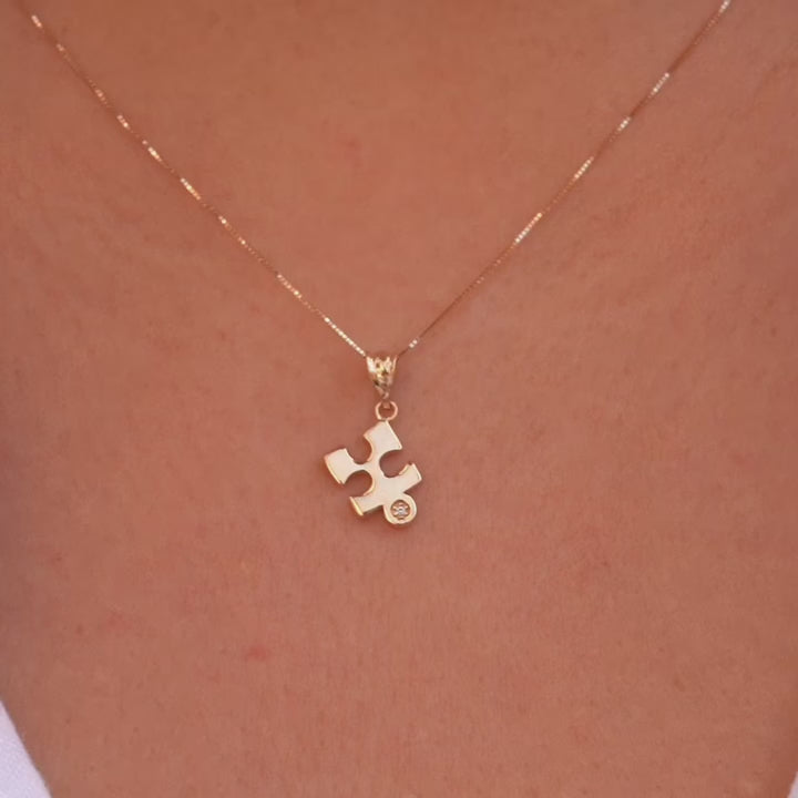 A model gracefully wears the 14K gold puzzle piece pendant on a fine chain, showcasing its subtle elegance and timeless design. The charm rests beautifully against the skin, adding a touch of meaning and sophistication to any outfit.