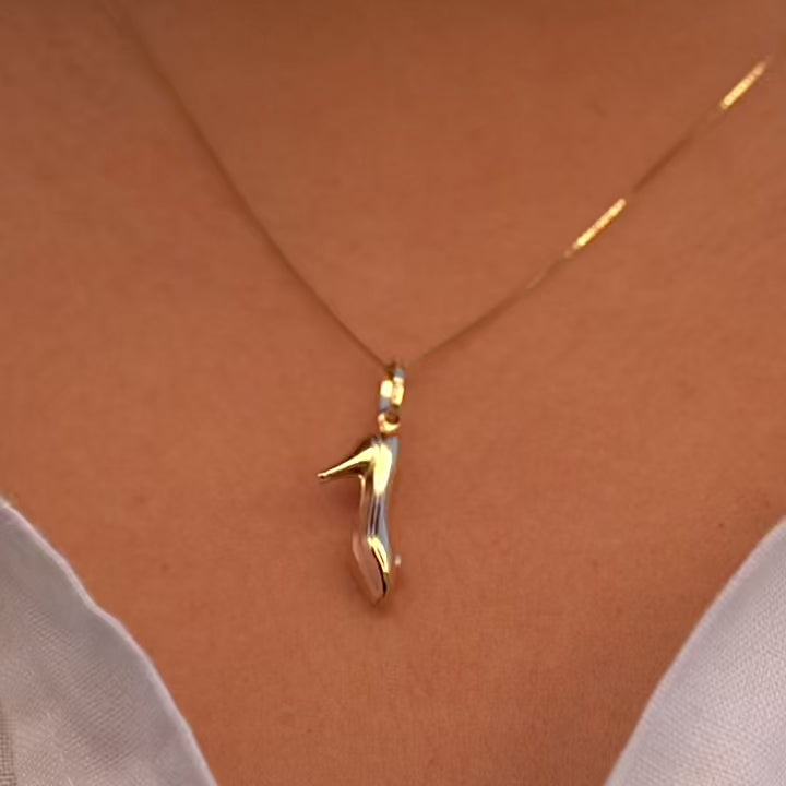 A model wearing the 14K solid gold high heel shoe charm pendant on a delicate gold chain around the neck. The charm rests just below the collarbone, adding a stylish and subtle touch to the model’s outfit. The lighting highlights the pendant’s rich yellow gold hue and refined craftsmanship, illustrating how this dainty charm enhances any fashion look with sophistication.