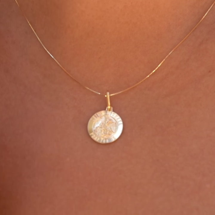 A woman wearing the 14K gold Saint Michael pendant on a delicate chain, resting elegantly against his chest, emphasizing its spiritual significance and timeless elegance.