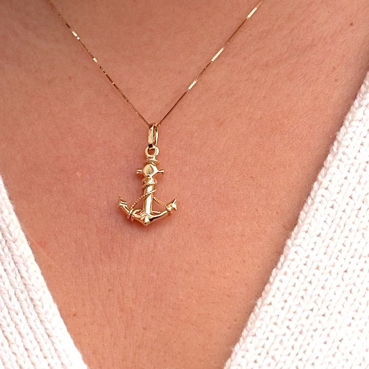 Model wearing a 14K gold anchor pendant on a delicate chain, showcasing the dainty nautical charm against the neckline for an elegant, maritime-inspired look.