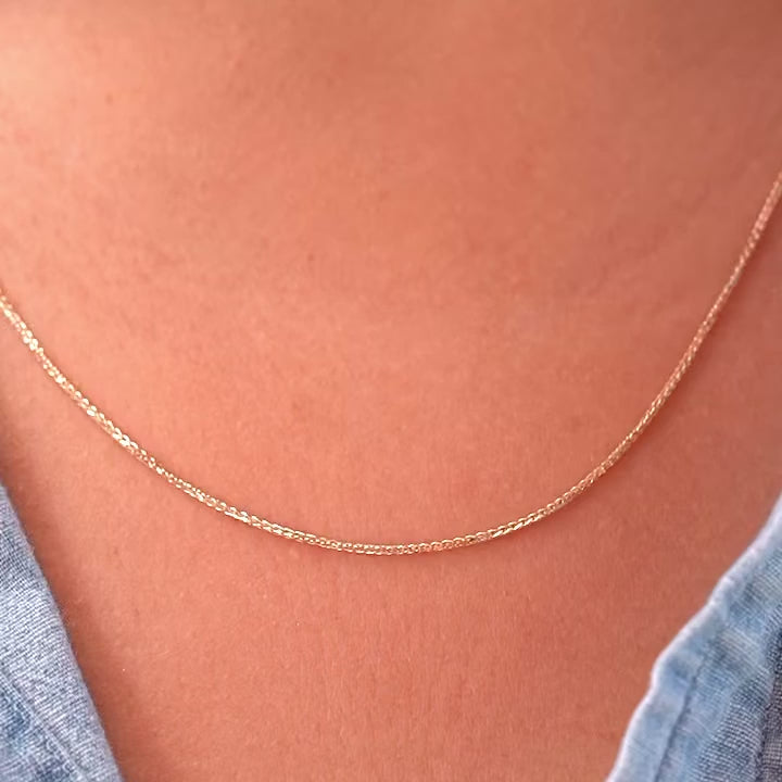 A model wearing a 14K yellow solid gold wheat chain necklace with 1.5mm flat open links, styled with a casual outfit to show the necklace’s versatility for both everyday and formal wear.