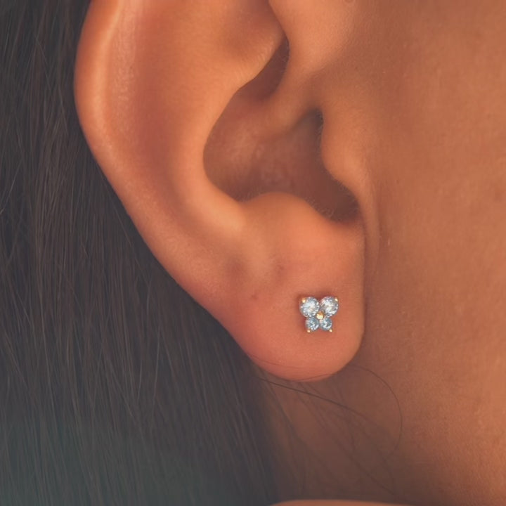 A model wearing 14K yellow gold butterfly CZ screw-back stud earrings, showcasing their delicate size and sparkling blue cubic zirconia accents for a chic everyday style.