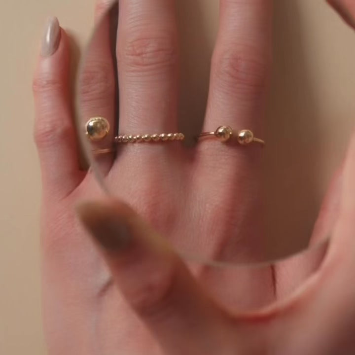 A model wearing a 14K yellow gold beaded ball ring, the polished gold spheres reflecting light beautifully as the ring adds a touch of subtle sophistication to her look.