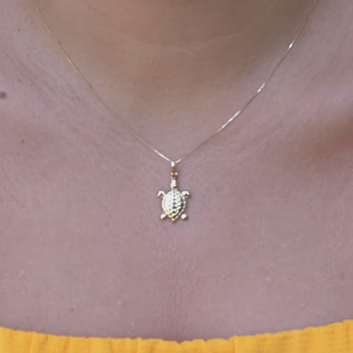 Model wearing the 14K gold turtle charm pendant on a fine chain, showcasing its delicate size and elegant shine on the neckline.