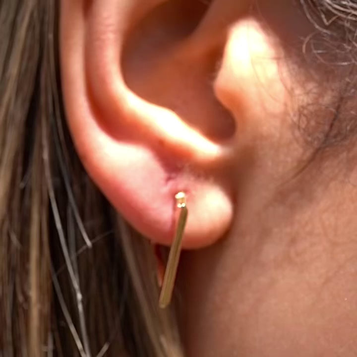 A stylish model wears the 14K Yellow Gold Triangle Hoop Earrings, with the dainty geometric hoops adding a modern, elegant touch to her everyday look.