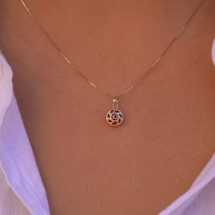 A model is wearing the 14K gold Evil Eye pendant with a red eye on a fine chain, allowing the charm to rest beautifully against the skin. The striking red eye adds a subtle yet meaningful touch, perfect for everyday wear.