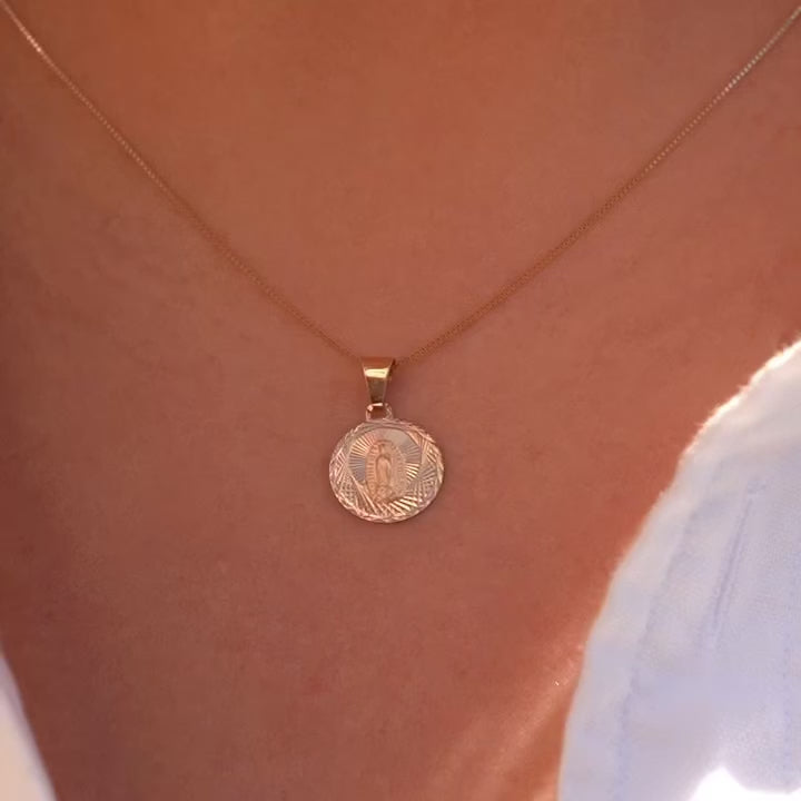 A model wears the 14K gold religious stamp pendant on a fine chain, the charm resting gently near the collarbone, blending timeless faith with everyday elegance.