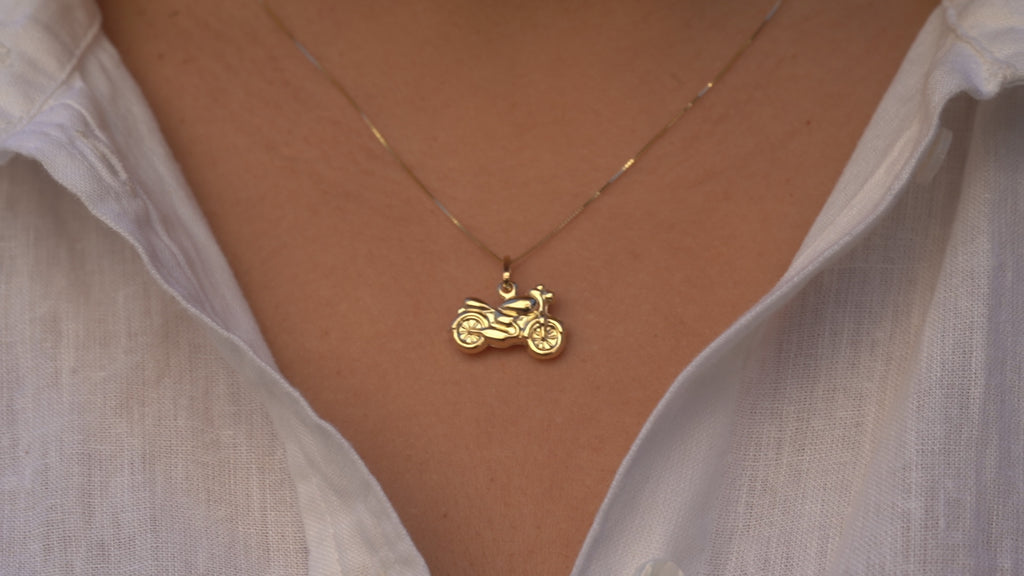 Video of a model wearing the 14K Gold Motorcycle Charm Pendant, showcasing its detailed motorcycle design, polished yellow gold finish, and elegant movement on a chain.